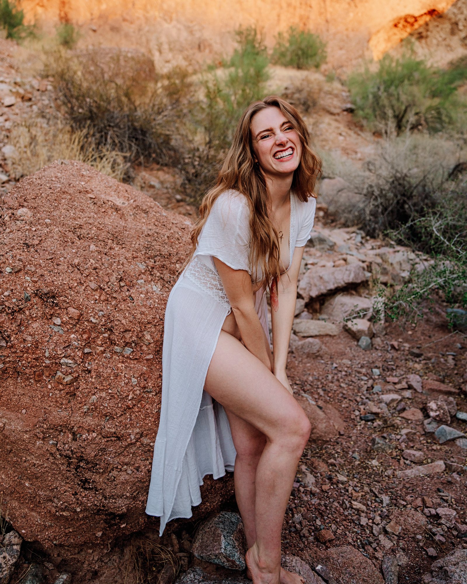 Madi standing on red rocks in the desert, white dress
