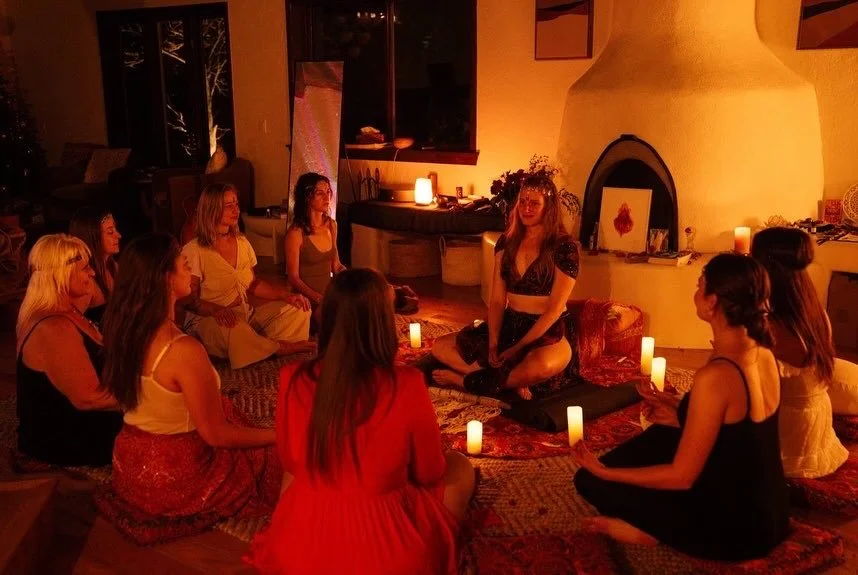 Candlelit women's circle around a kiva fireplace