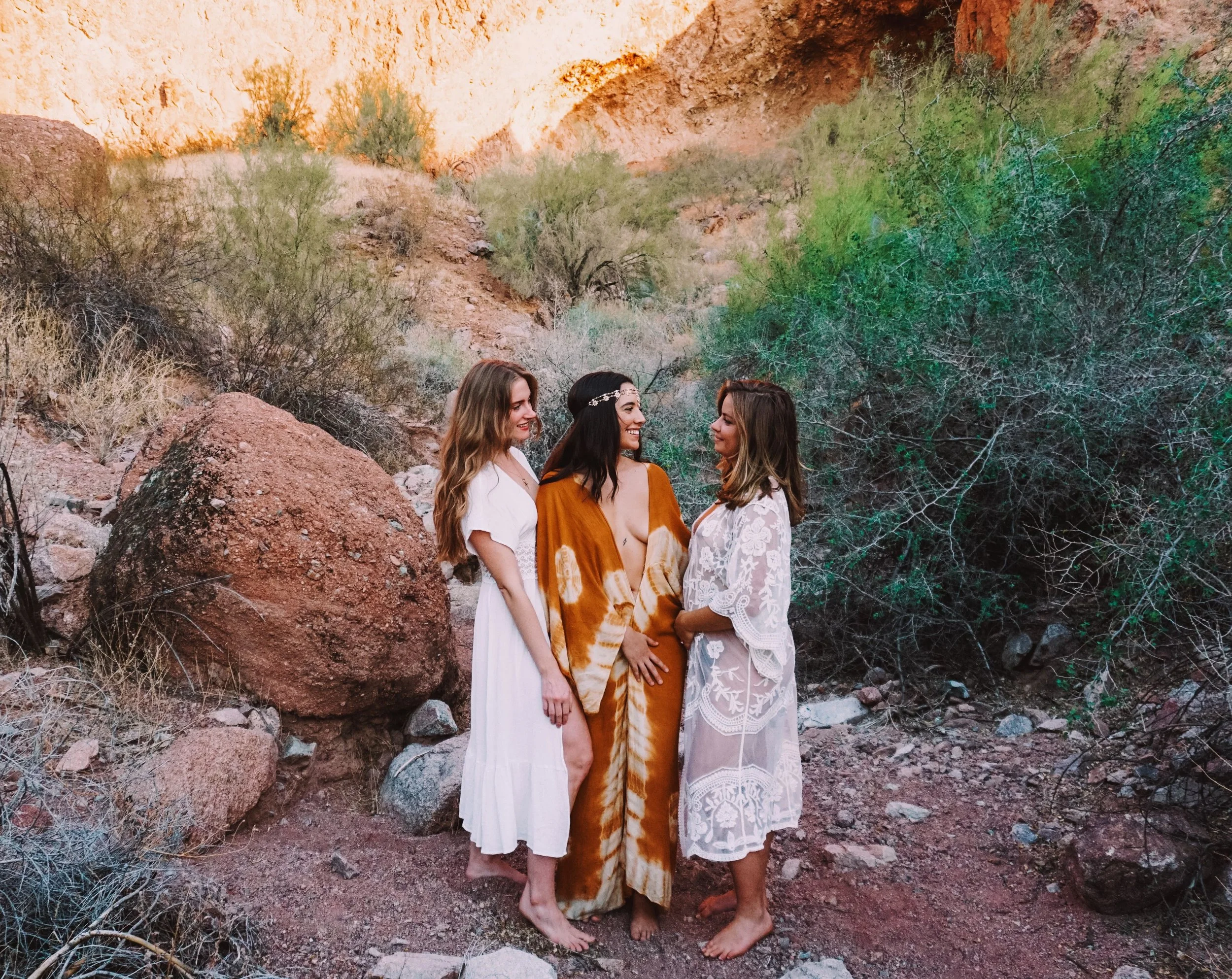 Three women standing together in a desert canyon